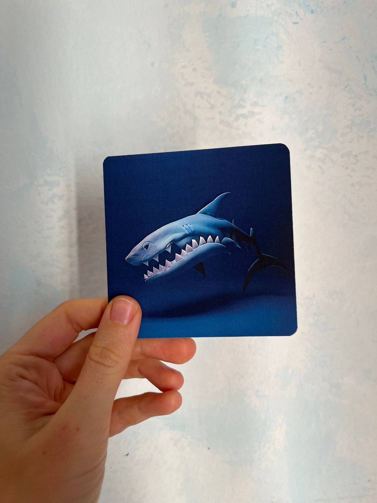 Child holding a shark-themed emotional card to reflect on feelings of strength and anger.